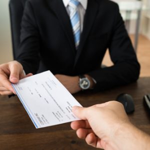 Close up of businessman hands giving cheque to client
