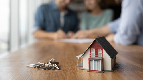 Close Up Of Key And Tiny Toy House On Table.