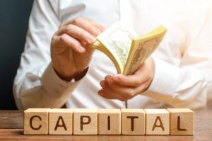 Businessman Counts Money On The Background Of The Caption Capital.