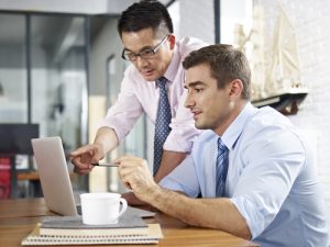 Asian And Caucasian Business Executives Looking At Laptop Screen