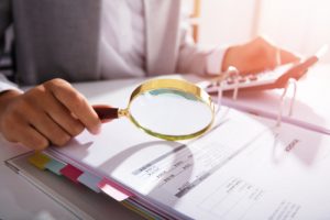 Photo Of Businesswoman Analyzing Invoice With Magnifying Glass