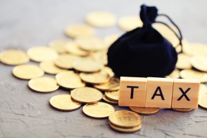 Word,”tax”,And,Black,Bag,On,Coins.,Tax,Concept.
